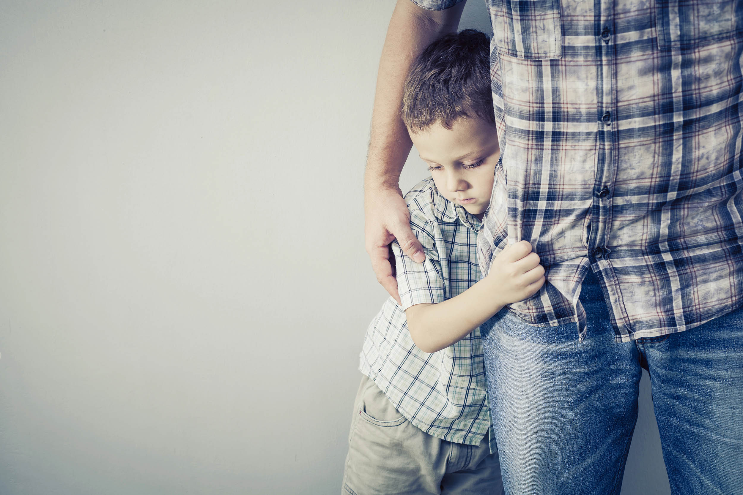Criança com ar triste agarrada a adulto