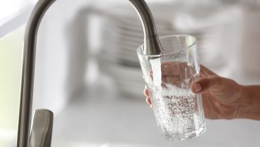 Woman pouring water into glass in kitchen