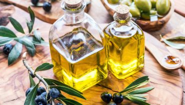 Olive oil and berries are on the olive wooden tray.