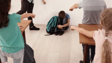 Bullied boy sitting on floor in classroom