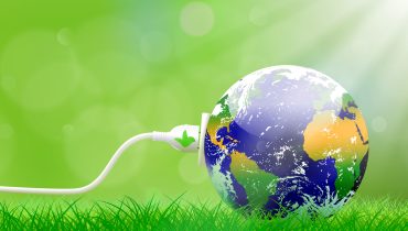 Green energy concept with Planet Earth and electric plug on lush grass