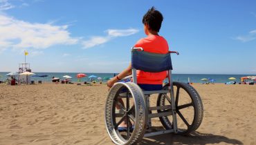 Criança em cadeira de rodas devido a doença rara, na praia