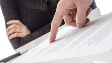 Hand showing a woman to sign a paper