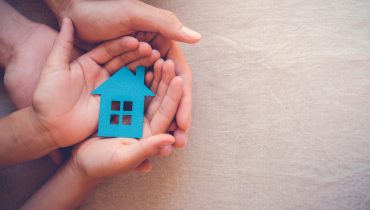Adult and child hands holding paper house