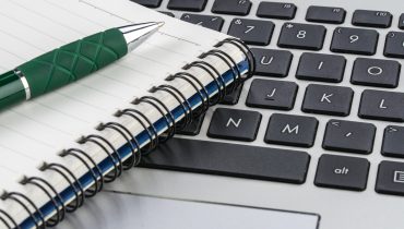 notebook and pen on the laptop keyboard