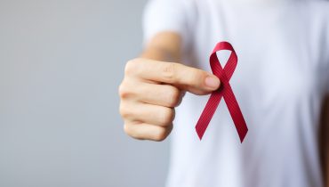 hand holding Burgundy Red Ribbon for March multiple myeloma Canc