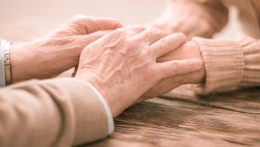 Two pairs of hands leaning on table