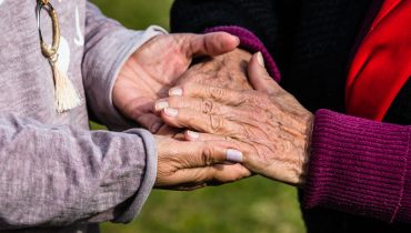Woman holding her old mother's hand giving her hope