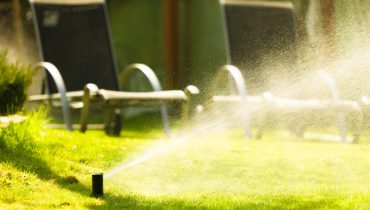Gardening. Lawn sprinkler spraying water over grass.
