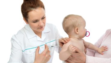 Doctors hand with syringe vaccinating child baby flu injection s