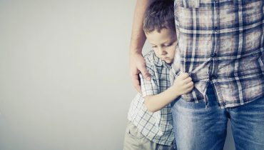 Criança com ar triste agarrada a adulto