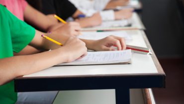High School Students Writing On Paper At Desk